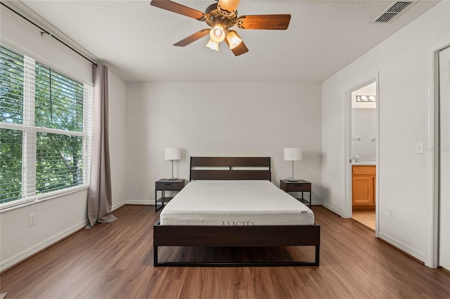 bedroom featuring ceiling fan, light hardwood / wood-style floors, and multiple windows