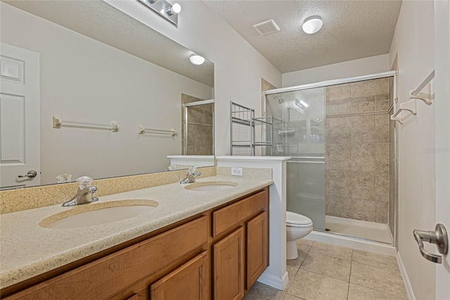 bathroom with double sink vanity, tile patterned floors, a textured ceiling, toilet, and walk in shower