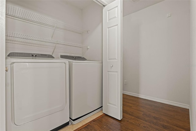 clothes washing area with washer and dryer and dark hardwood / wood-style flooring