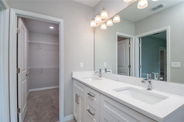bathroom with a sink, double vanity, visible vents, and a walk in closet