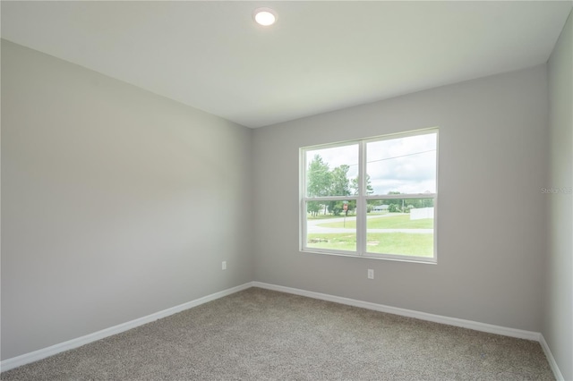 spare room with baseboards, recessed lighting, and light carpet