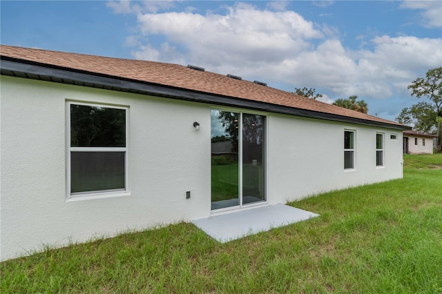 rear view of property featuring stucco siding and a yard