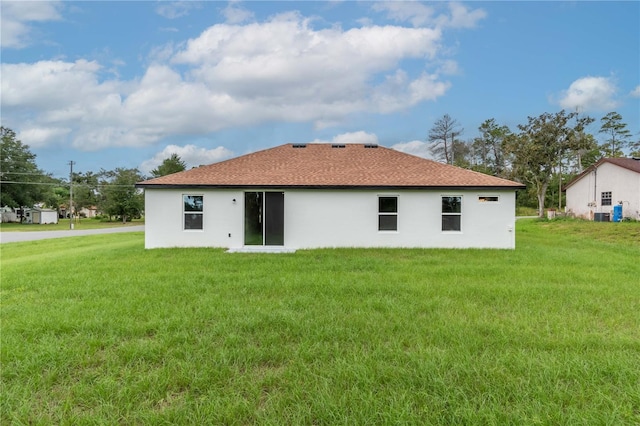 back of property with stucco siding and a lawn
