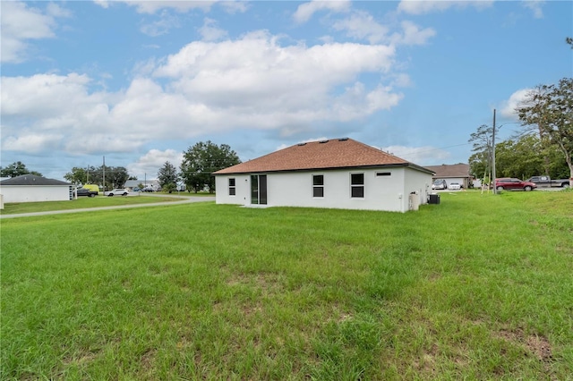 back of property with a lawn and stucco siding