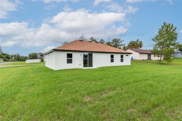 back of house featuring stucco siding and a yard