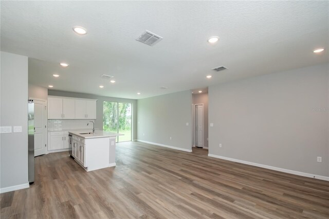 kitchen with open floor plan, light countertops, wood finished floors, and visible vents