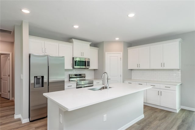 kitchen with sink, appliances with stainless steel finishes, a center island with sink, white cabinets, and light hardwood / wood-style floors