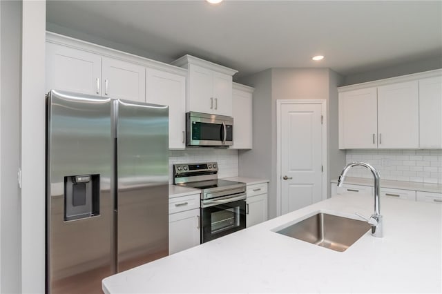 kitchen with backsplash, sink, appliances with stainless steel finishes, and white cabinetry