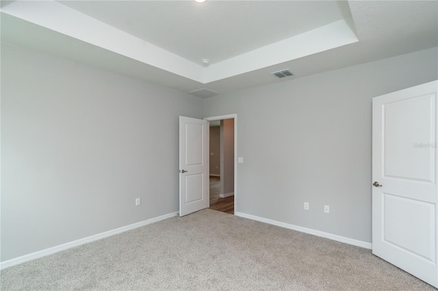 empty room with light carpet and a tray ceiling