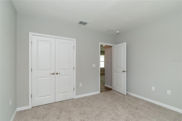 unfurnished bedroom with a closet, light carpet, and a textured ceiling