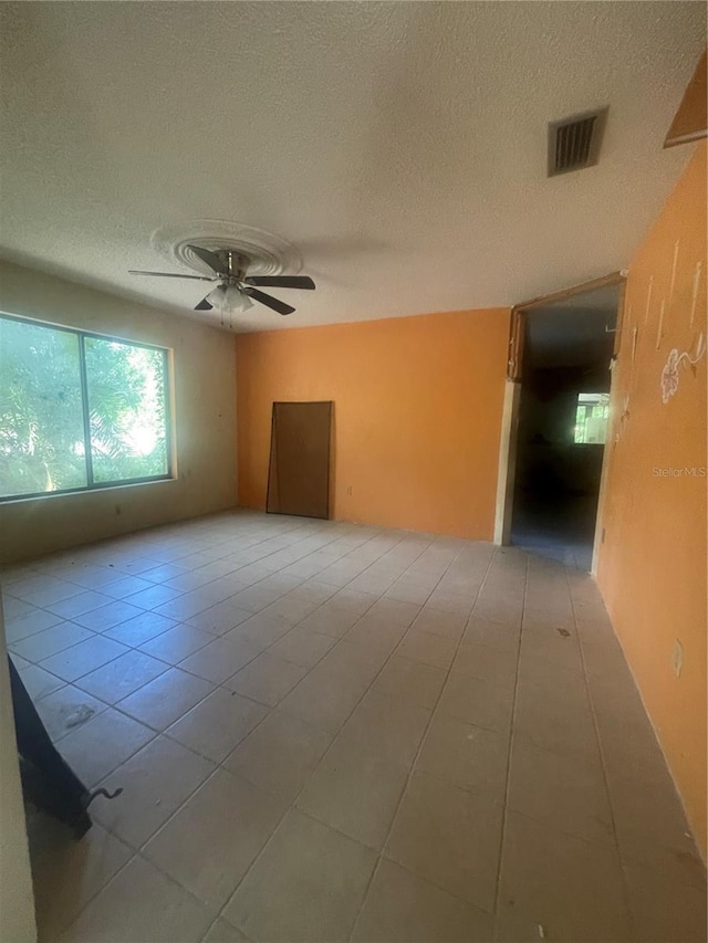 spare room with tile patterned flooring, ceiling fan, and a textured ceiling