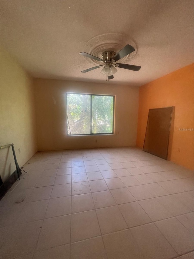 unfurnished room with ceiling fan, a textured ceiling, and light tile patterned floors