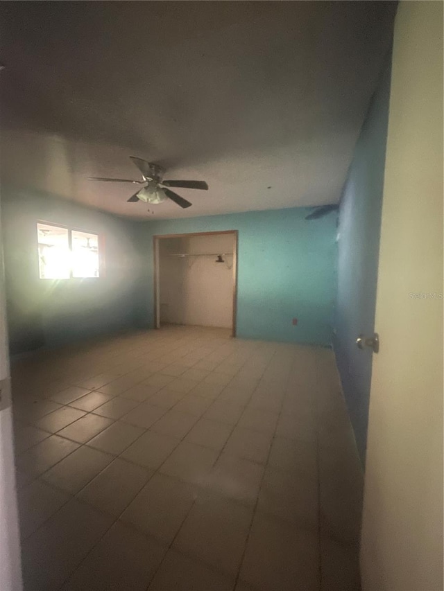 tiled spare room featuring ceiling fan