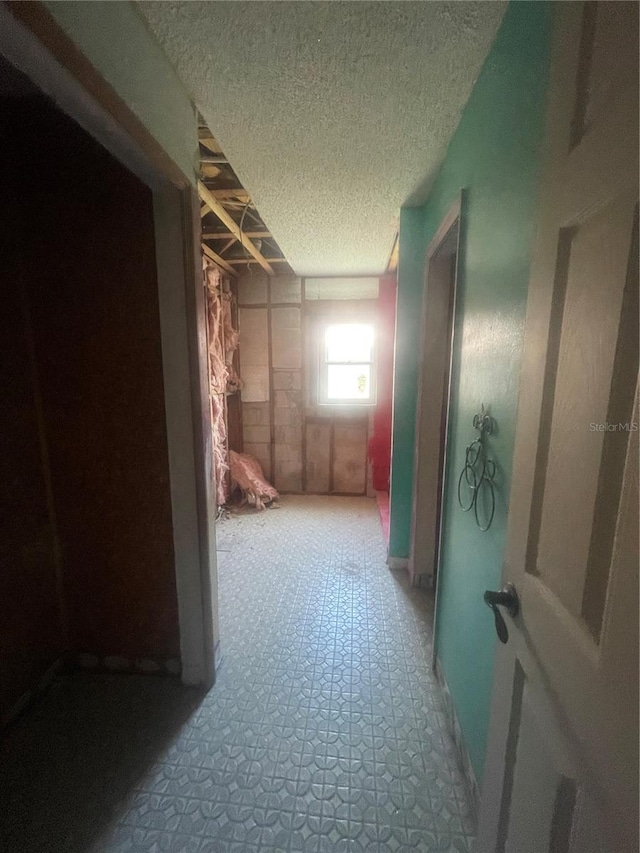 hallway with a textured ceiling and tile patterned floors