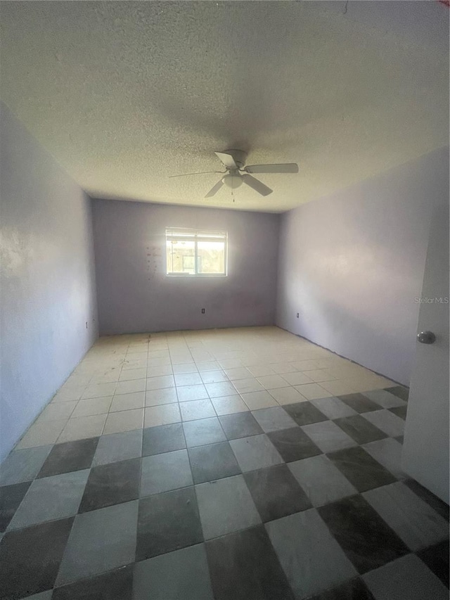 tiled spare room featuring ceiling fan