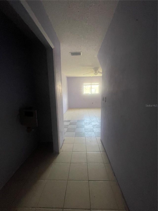 hall with light tile patterned floors and a textured ceiling