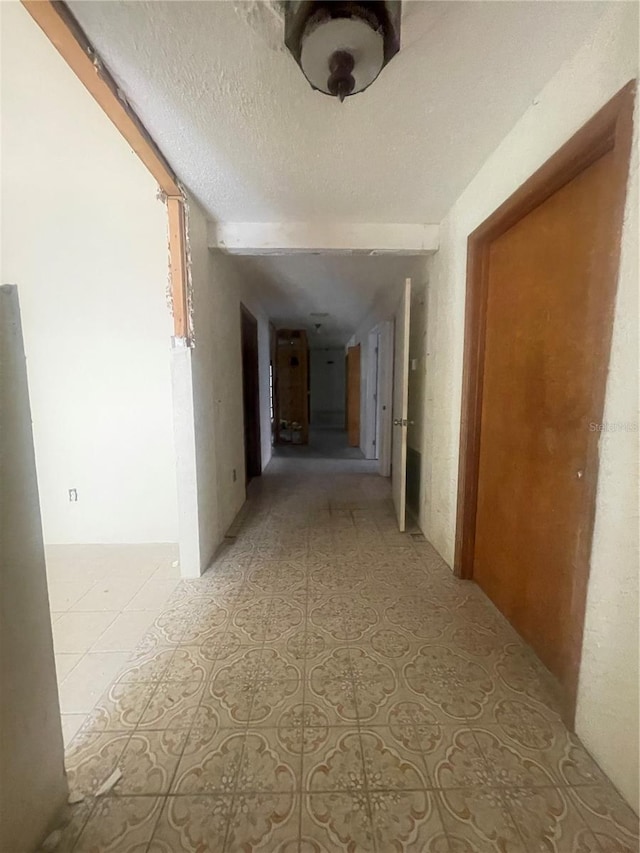 corridor with a textured ceiling and tile patterned floors