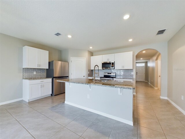 1502 Jadewood Way, Kissimmee, FL 34744 - kitchen featuring stone countertops, visible vents, white cabinetry, appliances with stainless steel finishes, and a center island with sink