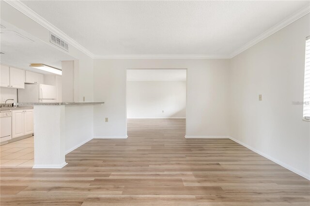 spare room with sink, light hardwood / wood-style floors, and crown molding