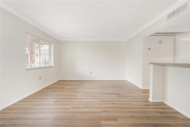 empty room featuring ornamental molding and light wood-type flooring