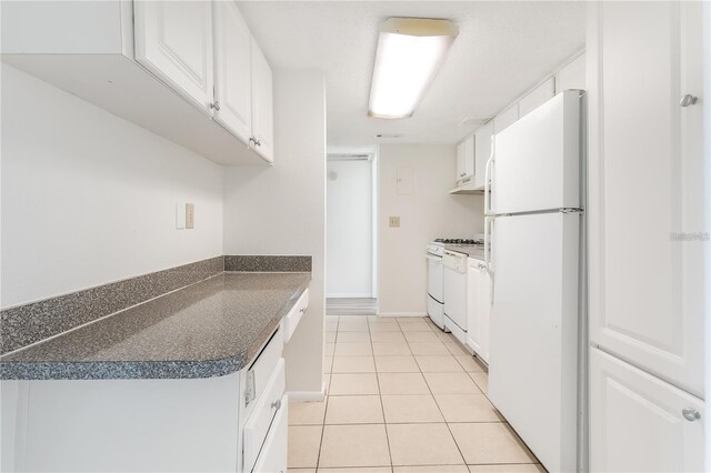 kitchen with light tile patterned flooring, white appliances, and white cabinets