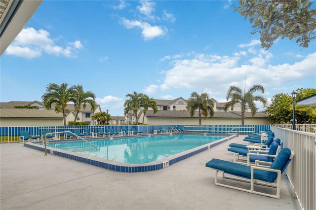 community pool featuring a residential view, fence, and a patio