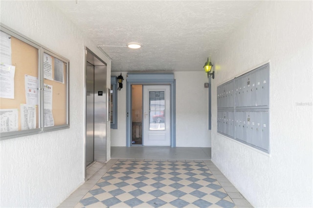 hall featuring elevator, mail area, a textured ceiling, and a textured wall