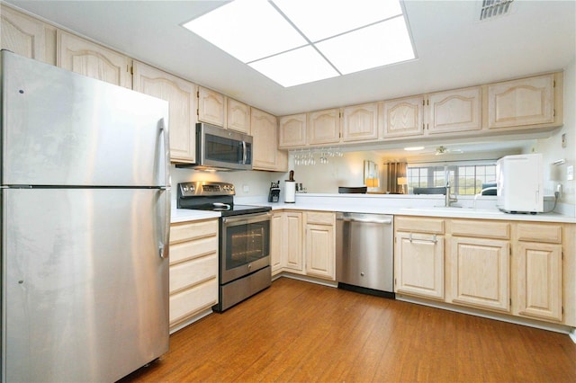 kitchen with stainless steel appliances, light countertops, visible vents, light wood-style flooring, and a sink