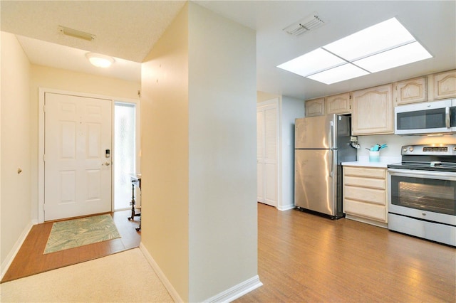 kitchen with visible vents, appliances with stainless steel finishes, wood finished floors, light countertops, and light brown cabinetry