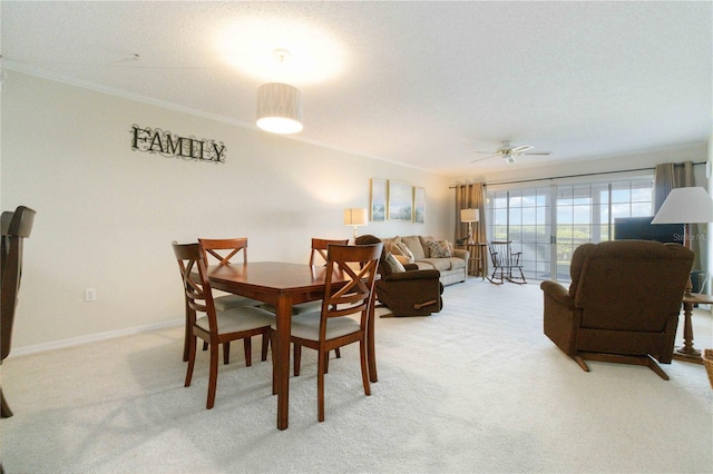 dining room with ornamental molding, light carpet, a textured ceiling, and baseboards