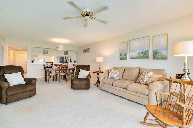 living area with carpet floors, a ceiling fan, and a textured ceiling