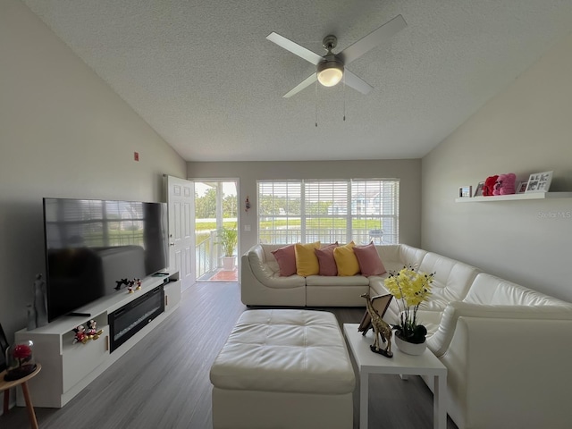 living room with ceiling fan, vaulted ceiling, wood-type flooring, and a textured ceiling