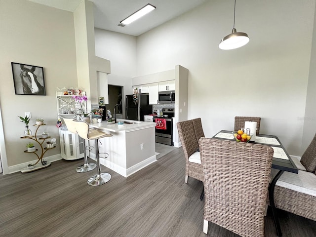 dining area with a towering ceiling, sink, and hardwood / wood-style floors