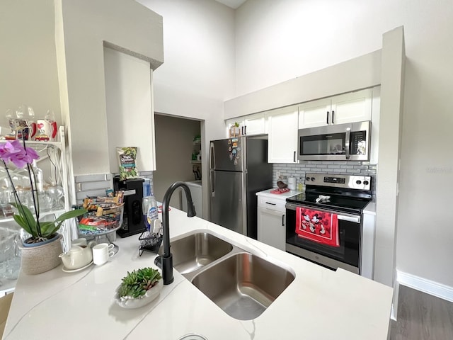 kitchen with decorative backsplash, hardwood / wood-style floors, white cabinets, sink, and stainless steel appliances