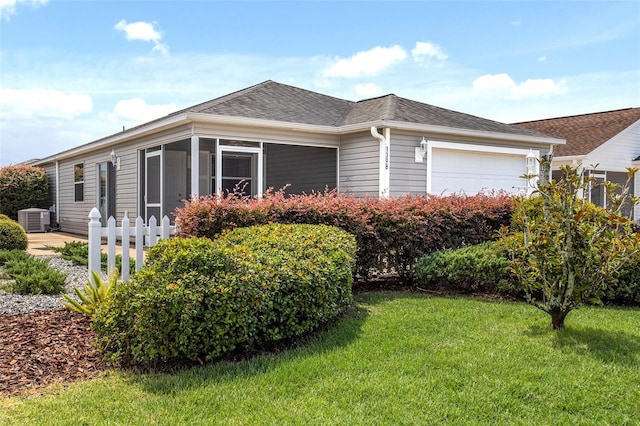 view of front of house featuring a garage, a sunroom, central AC, and a front lawn