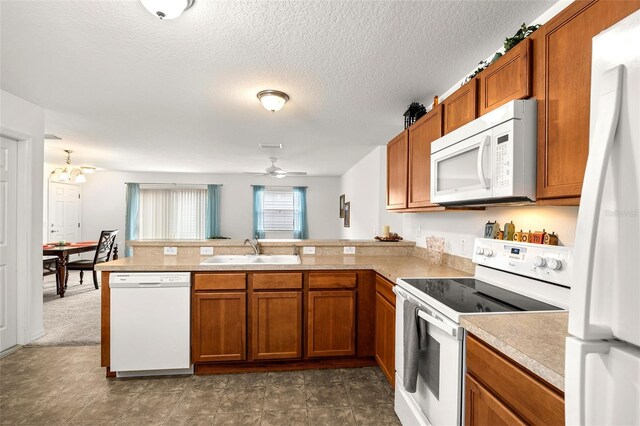 kitchen with dark colored carpet, ceiling fan with notable chandelier, sink, kitchen peninsula, and white appliances