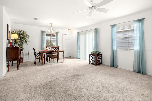 carpeted dining area with ceiling fan with notable chandelier