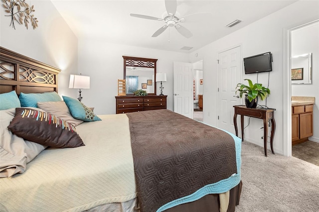 bedroom with ceiling fan, light carpet, and connected bathroom