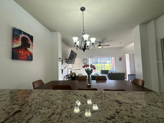 kitchen with a textured ceiling, ceiling fan with notable chandelier, and decorative light fixtures