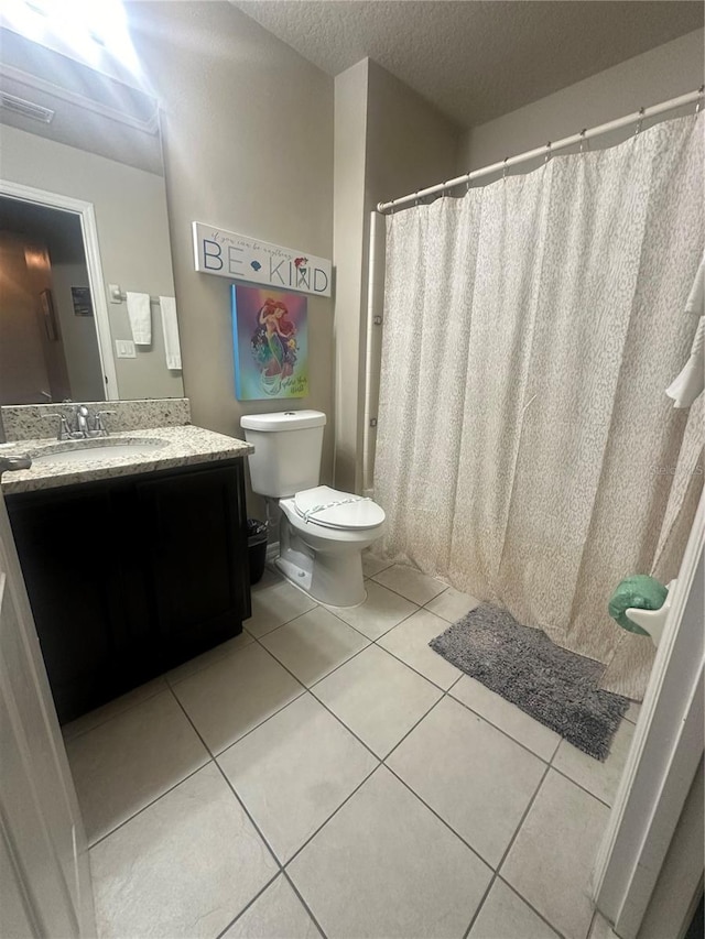 bathroom with tile patterned floors, vanity, a textured ceiling, and toilet