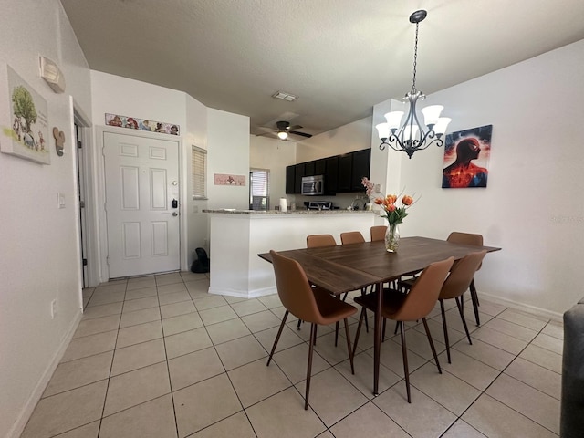 tiled dining space featuring ceiling fan with notable chandelier and a textured ceiling