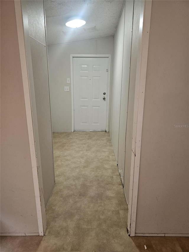 corridor with a textured ceiling and vaulted ceiling