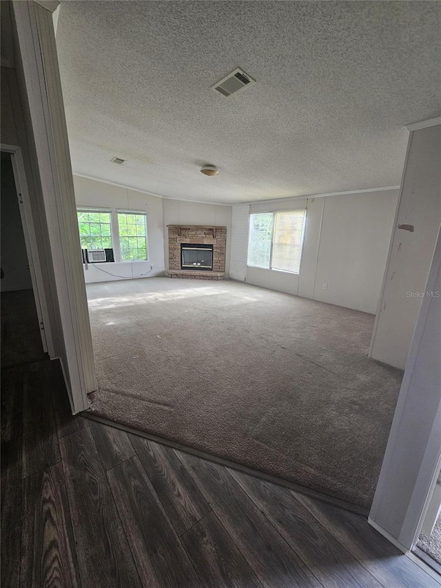 unfurnished living room with a fireplace, lofted ceiling, wood-type flooring, and a textured ceiling