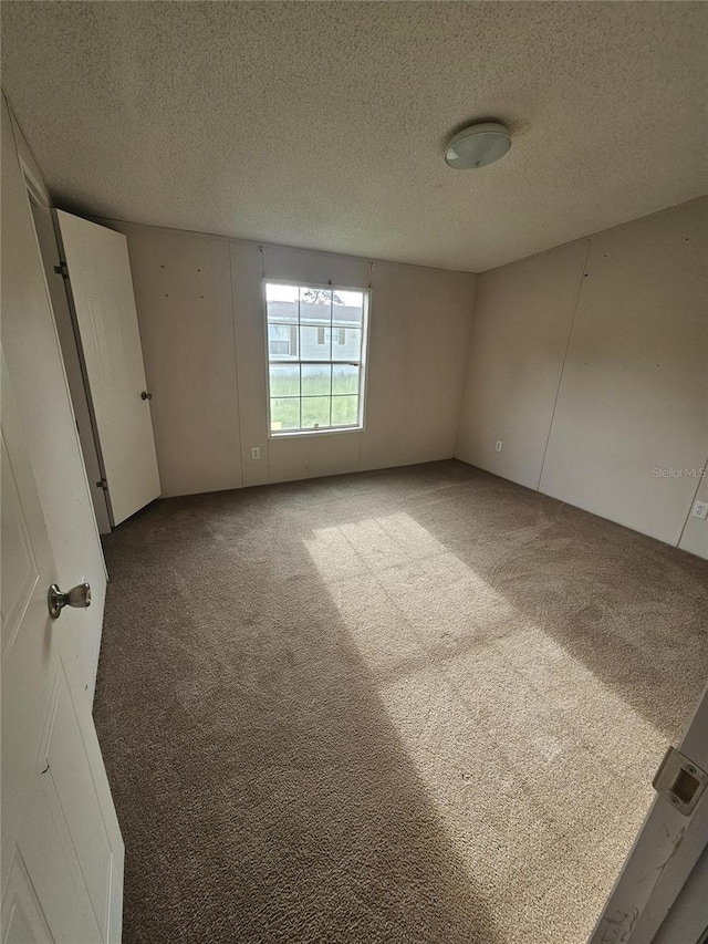 unfurnished room featuring a textured ceiling and carpet