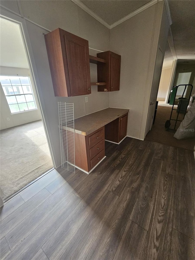 kitchen with built in desk, dark hardwood / wood-style floors, and crown molding