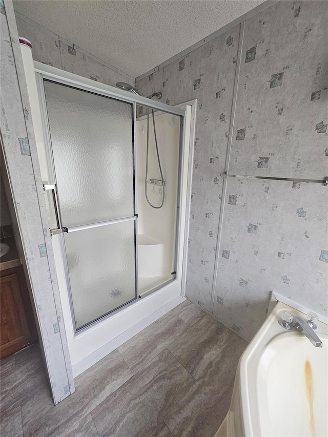 bathroom with a textured ceiling, hardwood / wood-style flooring, and an enclosed shower