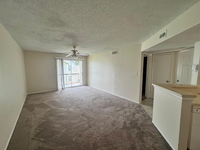 unfurnished room featuring baseboards, visible vents, light colored carpet, and a textured ceiling