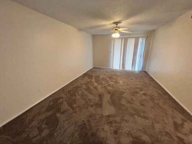 carpeted spare room featuring baseboards, a ceiling fan, and a textured ceiling