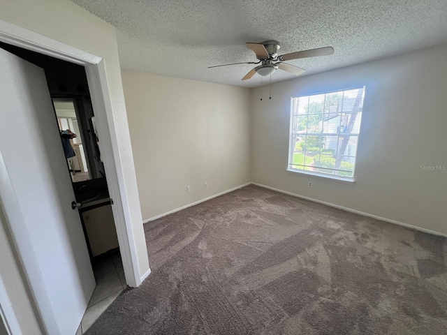 unfurnished bedroom featuring ceiling fan, a textured ceiling, baseboards, and carpet flooring