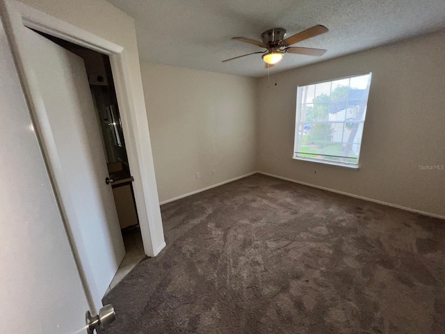 unfurnished bedroom featuring baseboards, dark colored carpet, and a ceiling fan